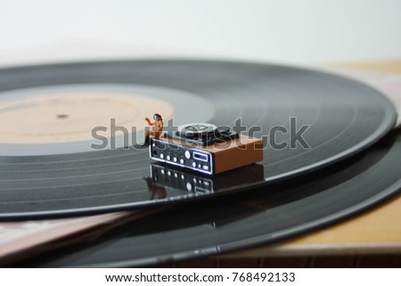 Miniature record player on a background of vinyl. Vintage or retro music listening concept. Listening party or audio entertainment. Appreciation of music, records, audio, songs and MP3's.