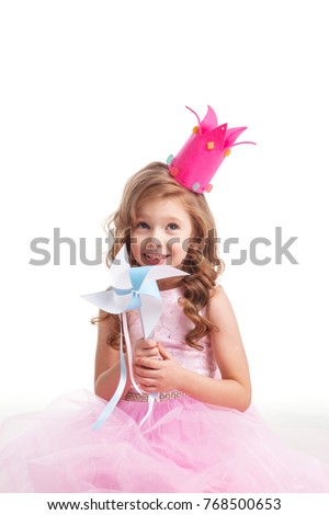 Beautiful little candy princess girl in crown holding pinwheel and smiling