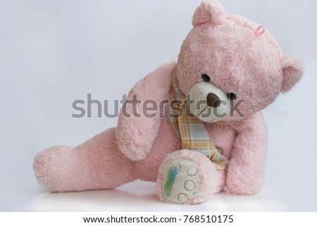 Old pink stuffed teddy bear doll, with colored paw and face; isolated on white background