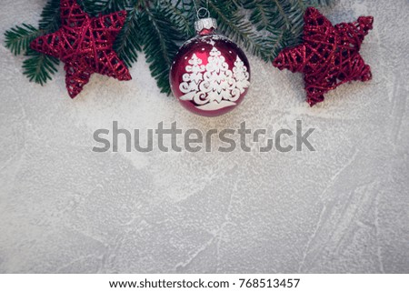 A light concrete Christmas background with fir tree branches and red ornaments. Top view. Close up. Copyspace