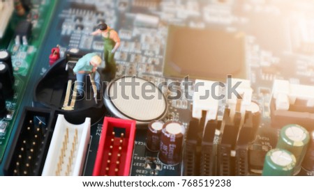 Miniature mini figures technician investigated the battery for the socket of the computer motherboard. concept of computer hardware. repairing upgrade and maintenance technology blurred background