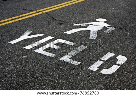 Warning at crossroad saying yield and person sign on asphalt