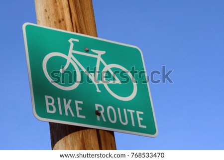 Bike route street sign on wooden pole against blue sky