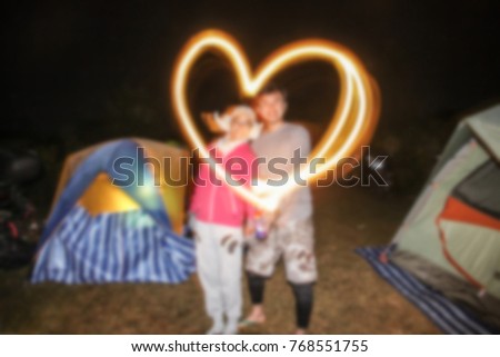 Blurred image.Men and women written with burning sticks and a long exposure at night at camping.Concept of image Valentine's day.