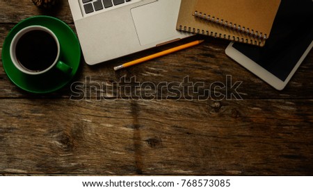 office stuff with laptop, tablet and green coffee cup with yellow pen notepad on the white desk top view at home