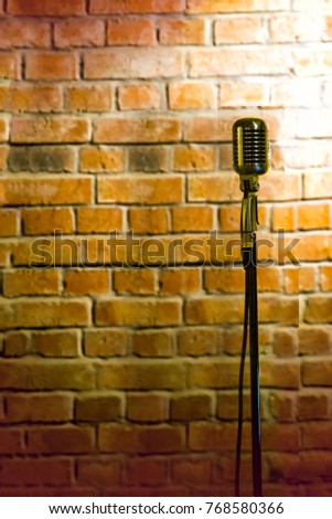 A microphone ready on stage against a brick wall ready for the Karaoke performer
