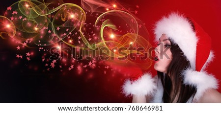 Woman in Christmas santa hat blowing flying magic glow star on red snow flame dream new year holiday background. Fashion girl create freeze fairy design of celebrate winter party.
