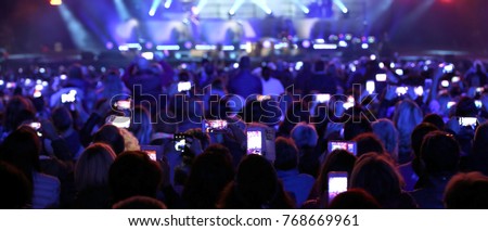 lots of gilrs and guys with the smartphone turned on to record or take pictures during the live concert