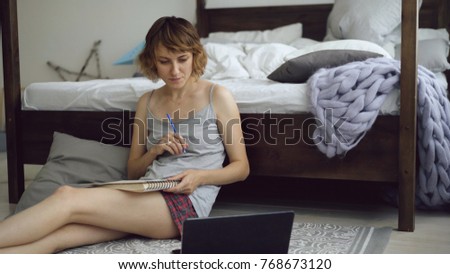 Cheerful young woman practice to draw sketch with pencils using laptop computer sitting near bed at home
