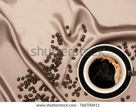 Flat lay of a cup of coffee on fabric cover with coffee bean scattered around