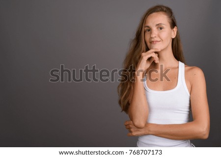 Studio shot of young beautiful woman with long blond hair against gray background