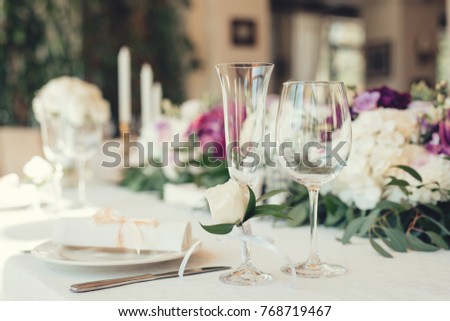 Wedding table served and decorated with flowers and candles, close up on whine glasses 