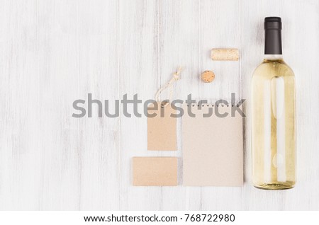 Mock up of blank beige kraft packaging, stationery, merchandise  with bottle white wine on soft white wood background, copy space.