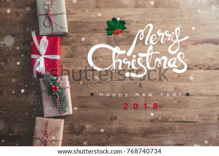 Merry Christmas and happy new year 2018 greeting text on wood table with decorated gift boxes at border, top view