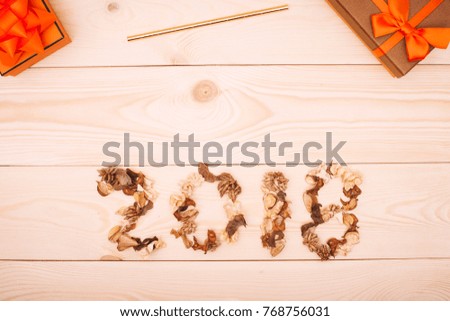 2018 inscription of dried flowers,orange and brown gift boxes and a gold straw at the top. Light wooden background. Top view. Copyspace.
