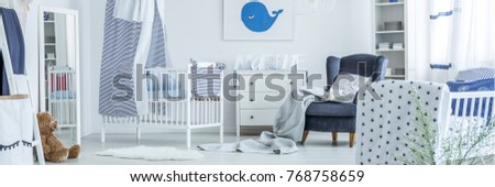 Child bed covered with a striped curtain, reflected in a mirror standing next to it