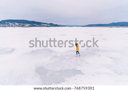 Young beautiful girl in yellow jacket is skating at winter on a frozen lake.