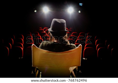 Young woman on director's chair on stage, in front of empty seats Royalty-Free Stock Photo #768762496