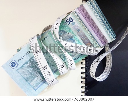 Measurement tape wrapped around money. Conceptual