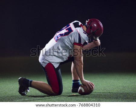 American football player starting football game on american football field at night