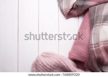 sweaters, warm pink clothes on a white wooden background