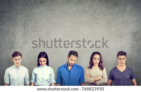 Group of sad unhappy people men and women standing against gray wall looking down. Negative human emotions  Royalty-Free Stock Photo #768823930