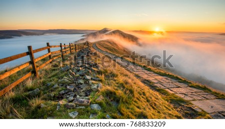 Thick cloud inversion with morning sun casting golden light on the landscape. Taken at Mam Tor in the English Peak District. Royalty-Free Stock Photo #768833209