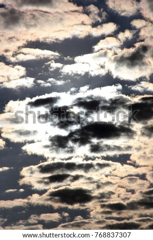 Altoculumus clouds silhoetted against the sun and deep blue sky