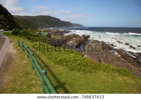 untouched coastal landscape with  breaking waves on the rocks and dense forest on the hills