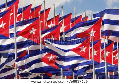 Cuban Flag On Flagpole Against Blue Sky With White Clouds