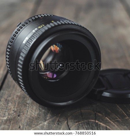 Old lens with color reflection on wooden background