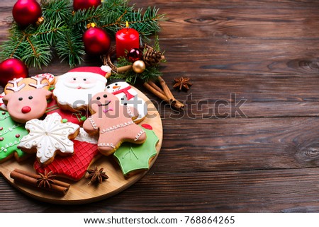 Various types of Christmas gingerbread cookies with fir tree branches, cinnamon sticks, anise star, candle and decoration close up on wooden table with copy space. Christmas holiday sweets food