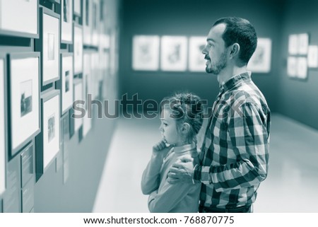 Young father and girl exploring exhibition of photos in museum