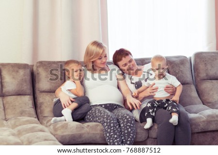 Three generations of women and children. Beautiful granny, mother and two sons boys are hugging, talking and smiling while sitting on couch at home