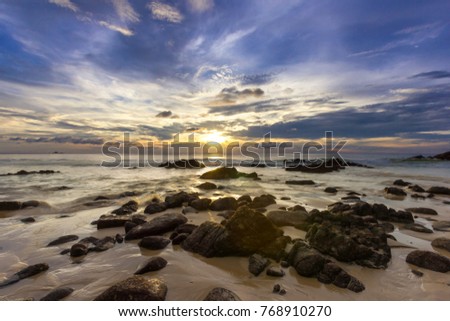 A beautiful seascape with motion of waves when low tide and twilight tropical sunset sky at Naithon Beach, Phuket, Thailand. Soft focus taken with slow shutter speed.