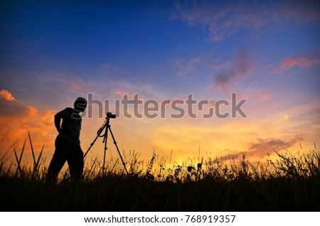 Man Photographer Taking Pictures during sunset. Silhouette Concept. Soft focus due to long exposure. 