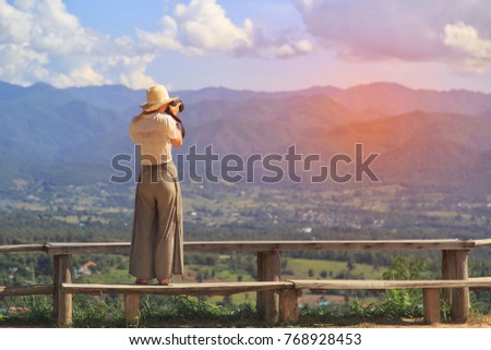 Female tourist traveler photographing at view point mountain peak. 
