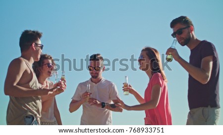 Young people partying and making a selfie on the beach. Medium shot. Soft Focus.