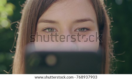 A young woman in the park using a phone. Closeup macro shot