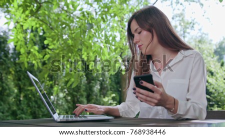 Business lady using a laptop and a phone. Medium shot. Soft Focus