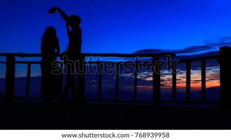 Silhouette of a loving couple taking selfie portrait photographer under colorful sunset sky background