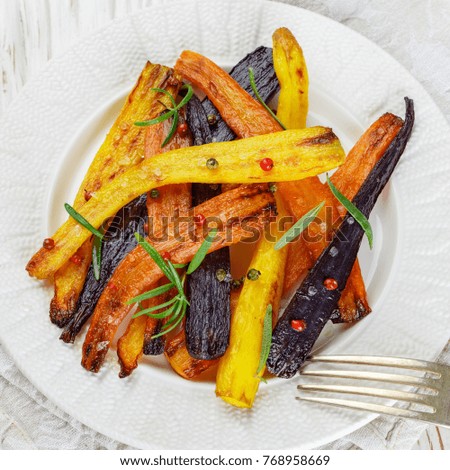 Roasted carrots with rosemary, coarse sea salt and pepper. Colorful vegetables and spices. Vegetarian dish. Selective focus. Square picture