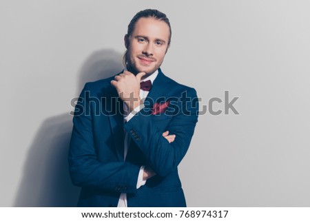 Portrait of attractive, caucasian, stunning, perfect man holding his hand near chin over grey background