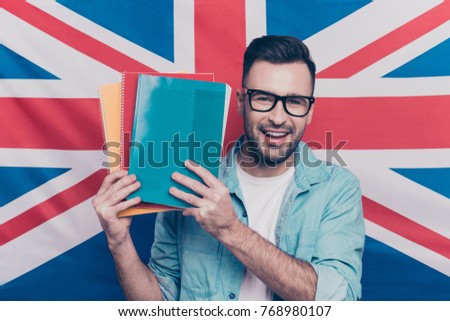 English language learning concept-portrait of cheerful attractive man with bristle showing colorful copy books standing over English flag background Royalty-Free Stock Photo #768980107