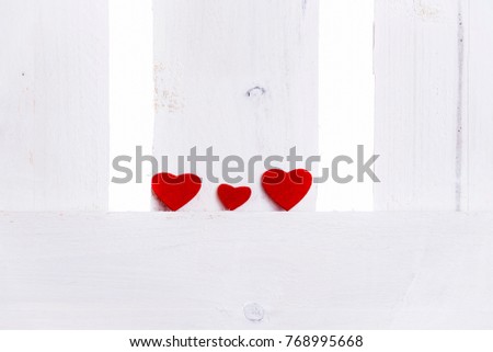 Family theme image with two big red hearts and a smaller one on the middle, on a white wooden fence. A concept for relationships, family, friends, feelings.