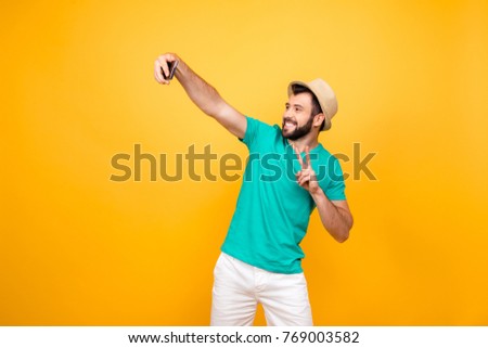 Hey what's up? Happy funky cheerful joyful man clothed in casual outfit taking a self portrait on his new smartphone and showing two fingers, copyspace