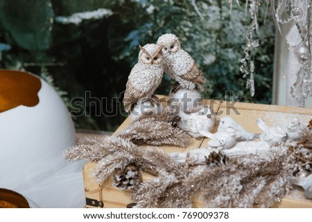 Two Christmas owls on a table near a decorative Christmas tree on a green background. New year Christmas tree. Christmas mock up.