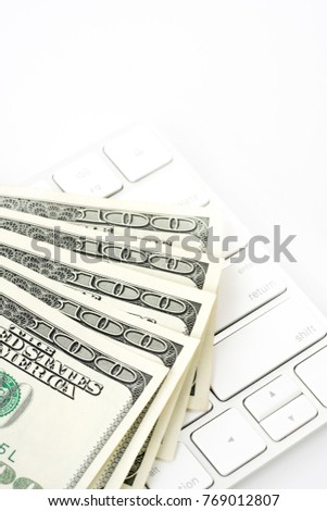 One hundred dollar bills and keyboard against white abstract background.