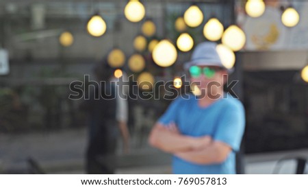 Defocused man standing and holding arms picture. Bokeh background.