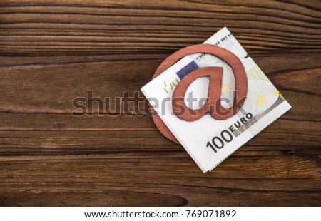 Concept, e-mail symbol, money one hundred euro bills in place against a tree texture background. idea: money transfer, earnings on the Internet, wallet.